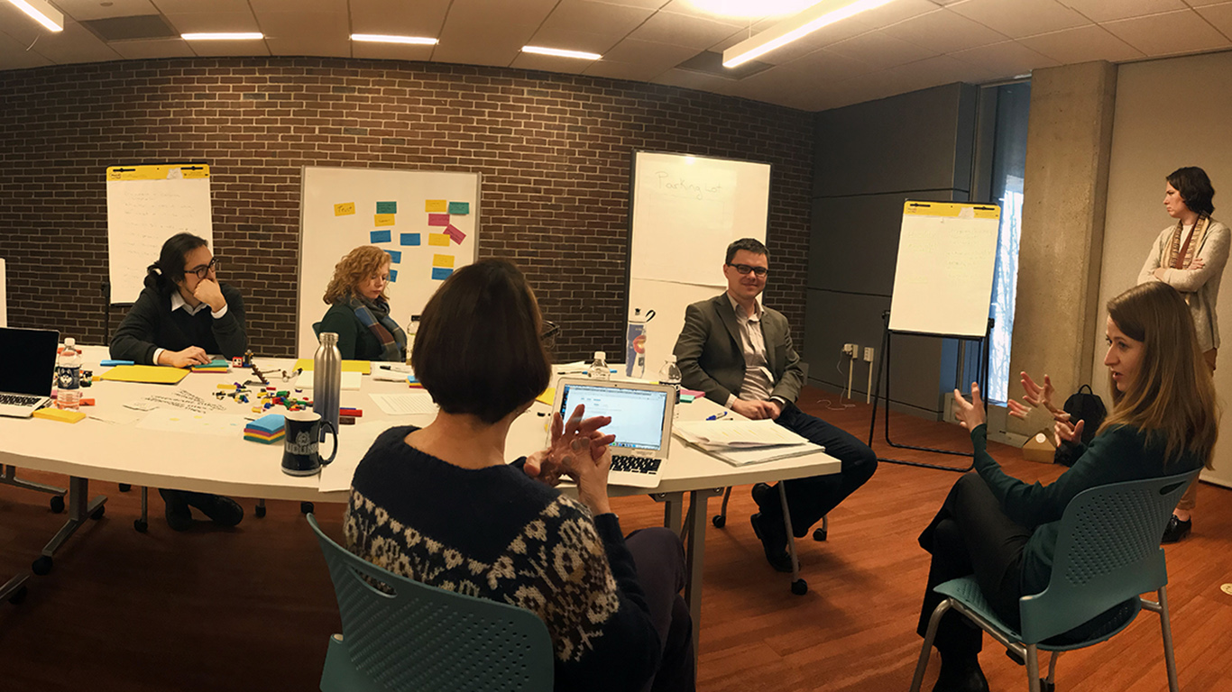 4 members of the HCPL2 team sitting around a table having a discussion